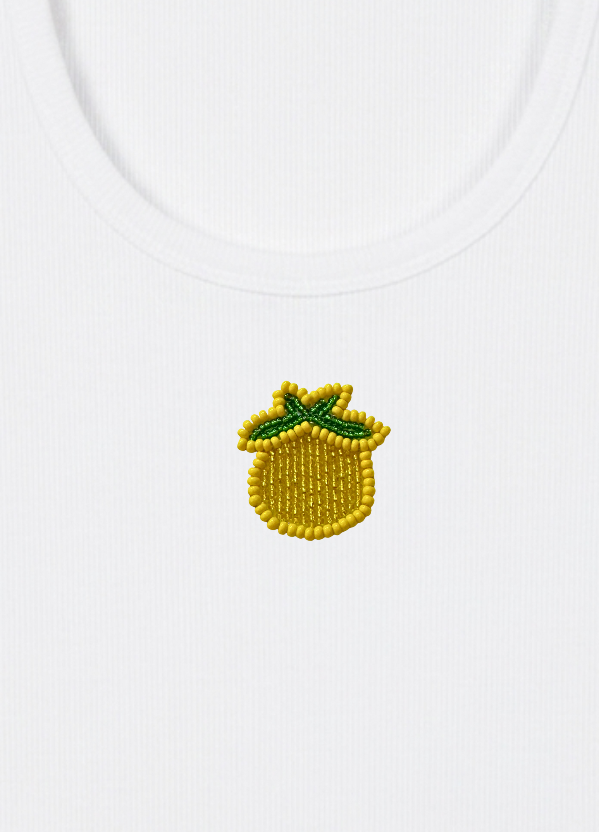 White tank top with a embroidered lemon design on a light yellow background