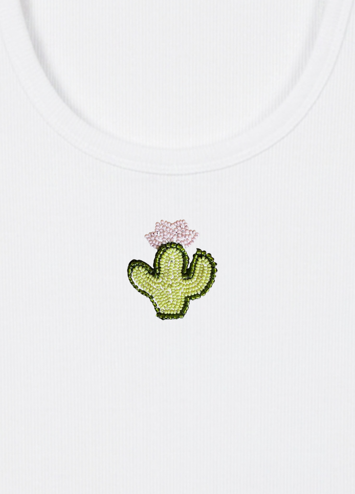 White tank top with a embroidered cactus design on a light yellow background